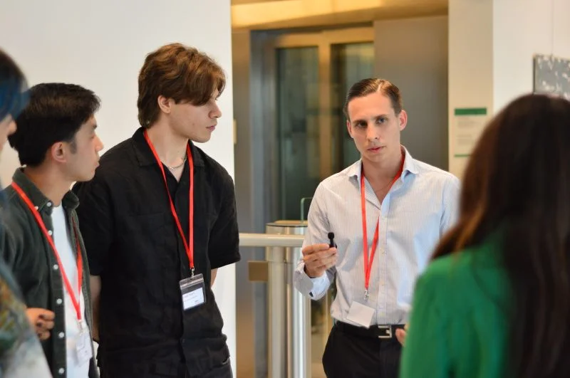 Team members wearing event lanyards discuss the project with other hackathon participants.
